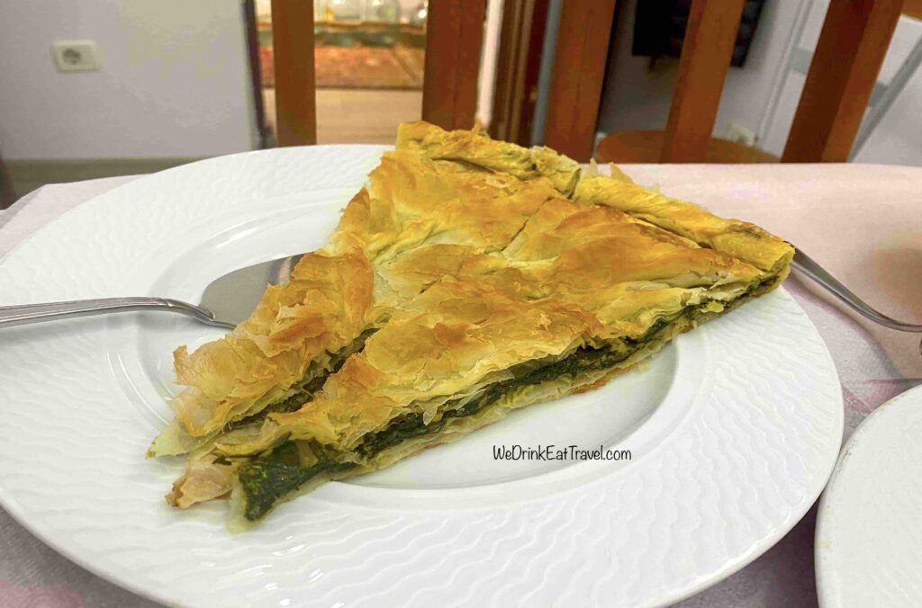 On a white porcelain plate are two long triangles of spinach byreks with flaky golden pastry at a restaurant in Tirana, Albania.