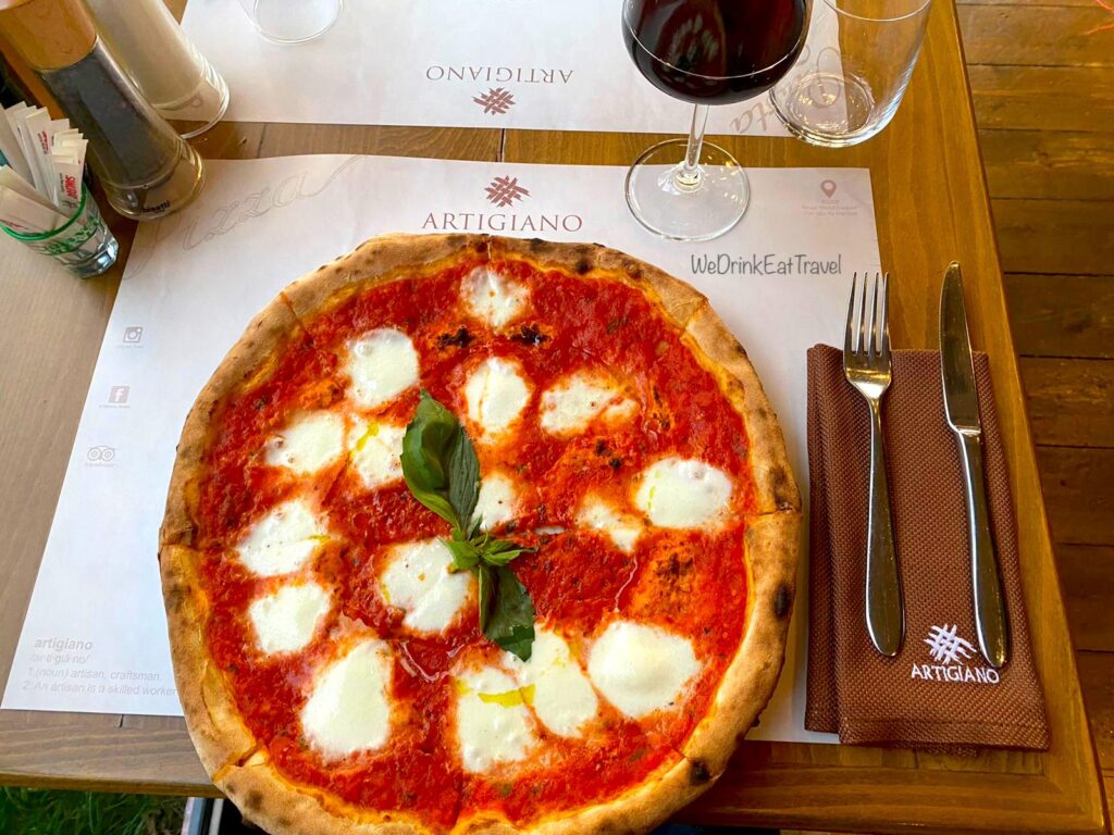 Close-up of a Margherita Pizza at the popular restaurant, Artigiano in Tirana, Albania, with a glass of red wine.