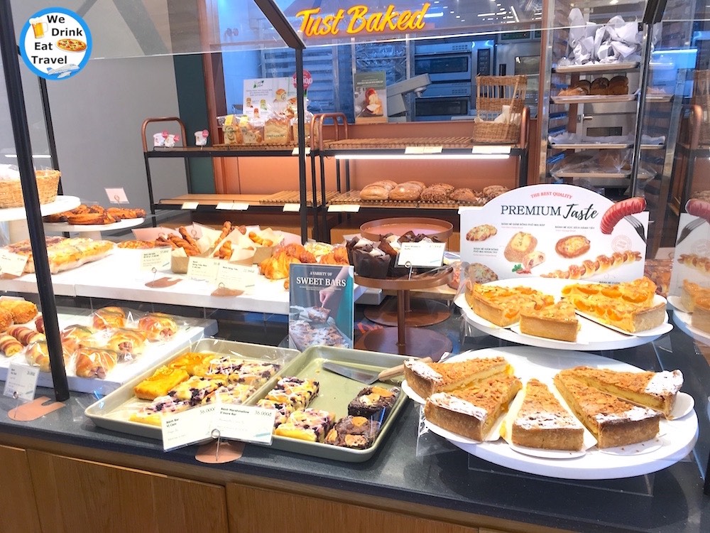 One of the top places to visit in Hanoi Vietnam for French pastries is Tous Les Jours, showcasing a range of pastries, cakes and breads under display cabinets and shelves.