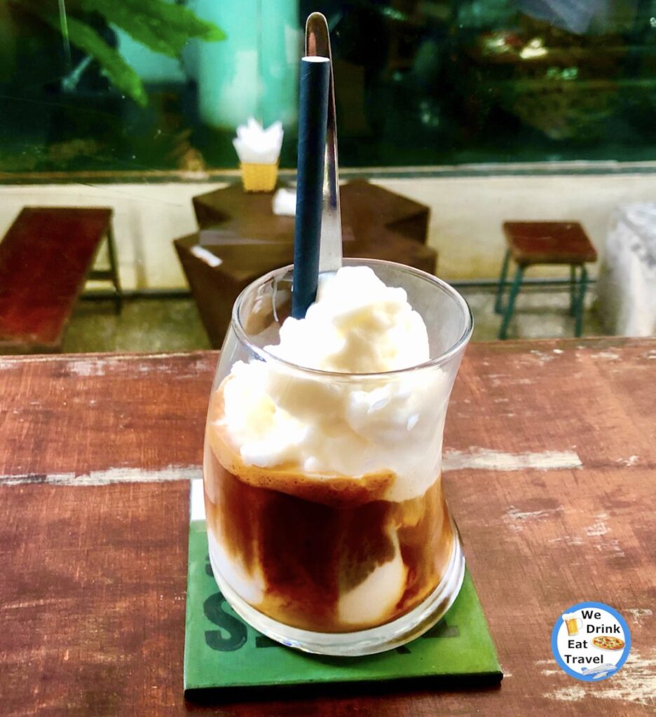 Close-up of a Vietnamese coconut coffee in West Lake, Hanoi, with a curved glass filled with strong coffee at the bottom, condensed milk and dollops of coconut ice-cream on top.