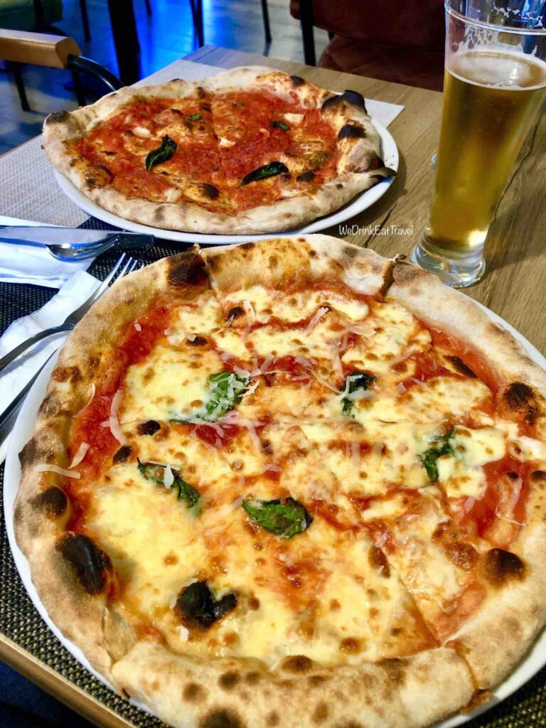 Close-up of two pizzas in Tirana, Albania one with lots of cheese and the other with lots of tomato sauce with a glass of beer.