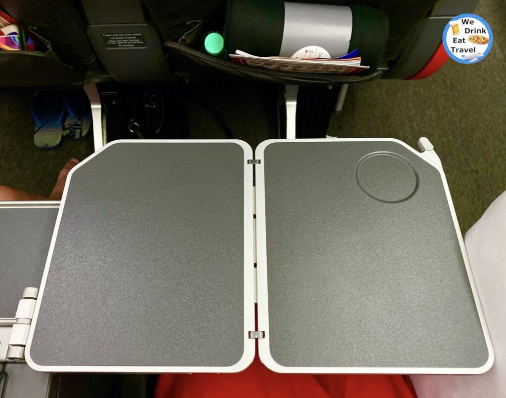 A small fold out table over a person sitting down for a Jetstar Business Class Flight from Bangkok to Melbourne.