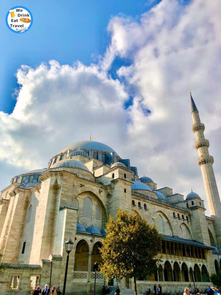 One of the top free things to do in Istanbul, Turkey is see Suleymaniye Mosque, with its grand blue domes and tall minaret against a bright blue sky filled with white clouds.