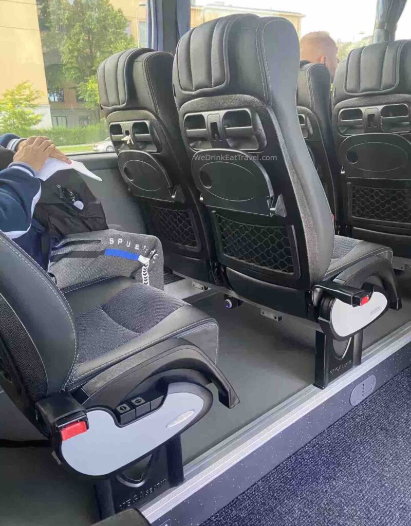 Close-up of paired seats on a Flixbus tour bus with seat reclining functions, tray table, drink holders and storage area.